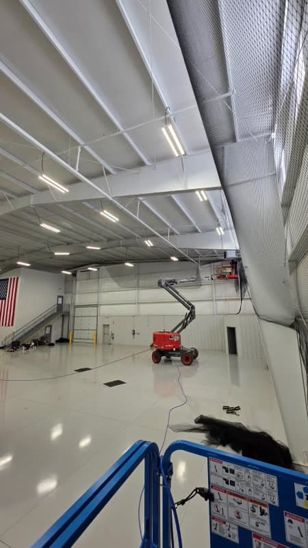 Large white warehouse with bird netting installed on ceiling and skylights