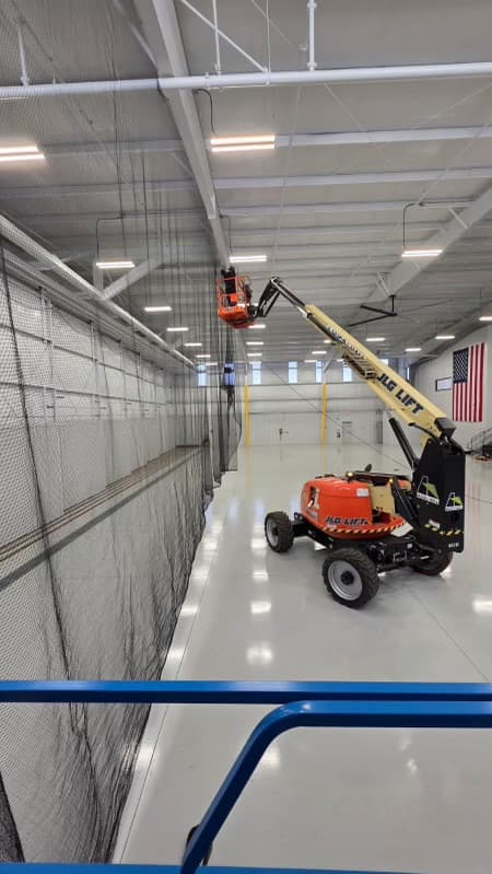 Warehouse floor with bird netting wall installation and boom lift