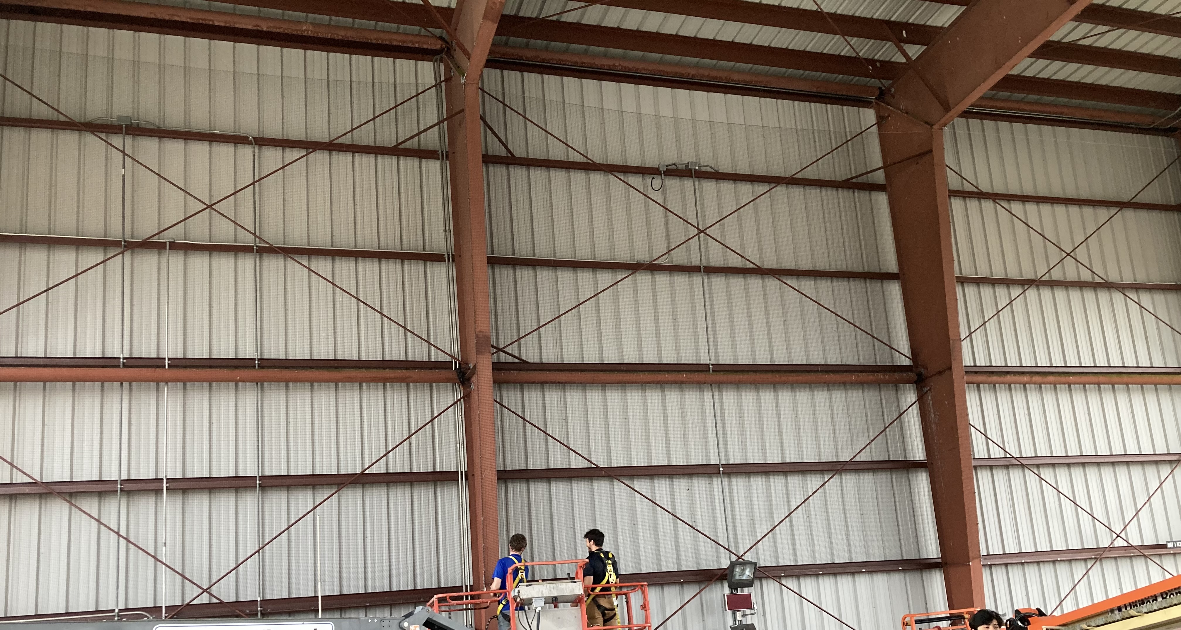 Technicians installing bird netting on industrial metal framework